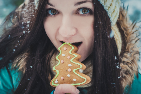 Winter smiling girl eating oatmeal and Gingerbread Cookie outdoor.の写真素材