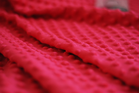 Fluffy Gentle baby red fabric with dots. Soft pastel textile texture. Folds on the soft fabric.