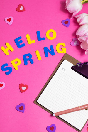 Composition with blank notebook, words Hello Spring and beautiful tulip flowers on pink backgroundの写真素材