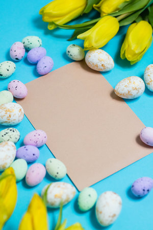 Yellow tulip flowers and easter eggs on blue background. Top view with copy space. Happy easter greeting cardの写真素材