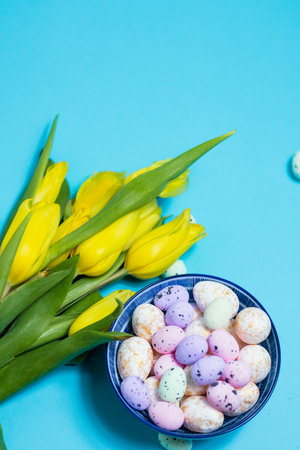 Yellow tulip flowers and easter eggs on blue background. Top view with copy space. Happy easter greeting cardの写真素材