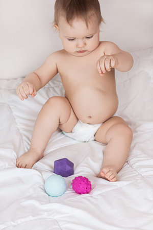 A toddler plays with rubber balls to develop motor skills and tactile sensations. High quality photoの写真素材