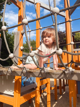 Baby toddler on the playground in a web of ropesの写真素材