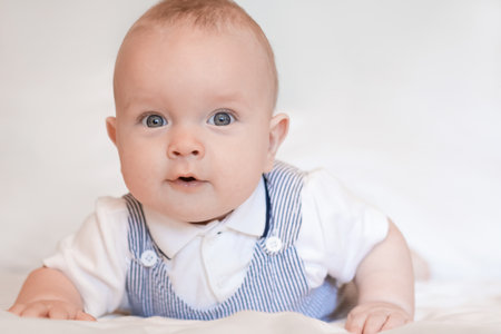 Portrait of a stylish baby boy on a bed.の写真素材