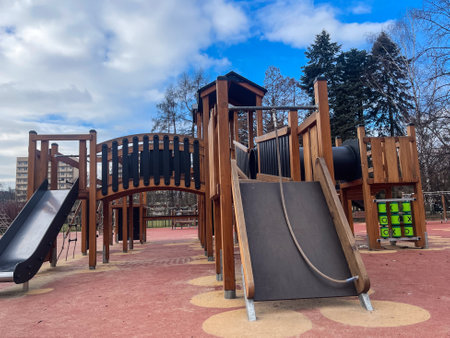 Children enjoy outdoor play at a vibrant playground under a bright, cloudy skyの写真素材