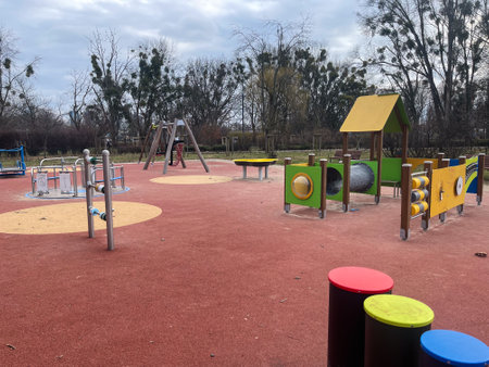 Children enjoy outdoor play at a vibrant playground under a bright, cloudy skyの写真素材