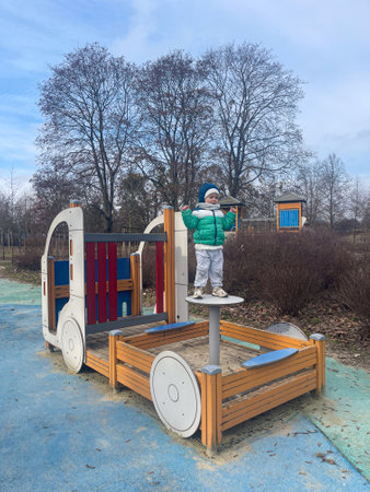 Child playing on a colorful playground structure in a park during a winter afternoonの写真素材
