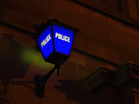 A blue lamp outside a police station at nightの写真素材