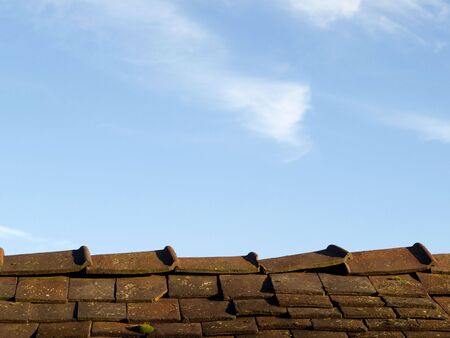 A roof with cracked tiles against blue sky backgroundの写真素材