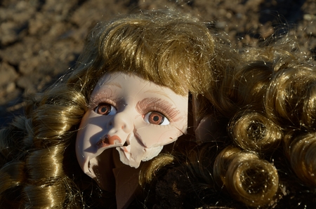 Broken head of porcelain doll lying on the groundの写真素材