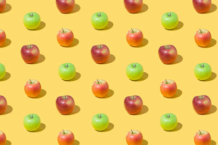 Creative pattern made of red and green apple fruit on yellow background. Minimal colorful concept.