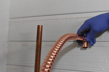 Gloved Hand Holding Copper Water Heater Supply Line Estimating Heightの写真素材