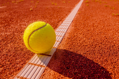 Yellow tennisball on the line at a clay courtの写真素材