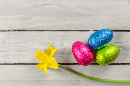 Easter eggs and a daffodil on a wooden table