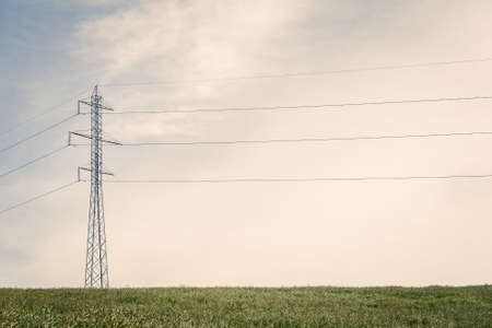 Tall pylons with wires on a green fieldの写真素材