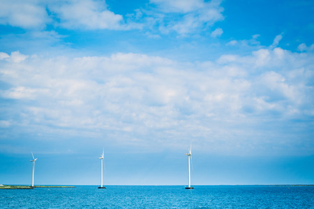 Windmills on a row in the blue oceanの写真素材