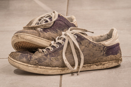Dirty shoes with mud and soil on a floorの写真素材