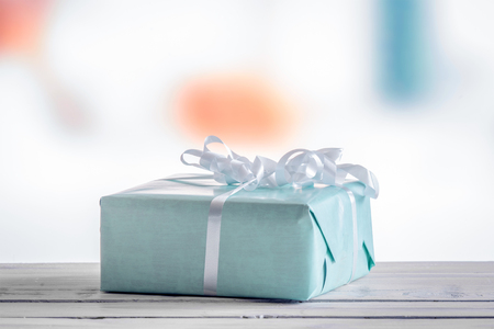 Blue present on a wooden table in daylightの写真素材