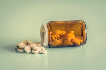 Orange glass of pills on a blue tableの写真素材