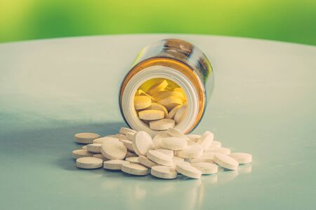 Pills coming out of a glass on a tableの写真素材