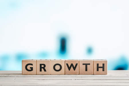 Growth sign made of wooden cubes on blue backgroundの写真素材