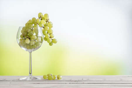 Grapes in a vine glass on a wooden tableの写真素材