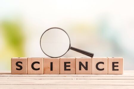 Science sign with a magnifying glass on a wooden tableの写真素材