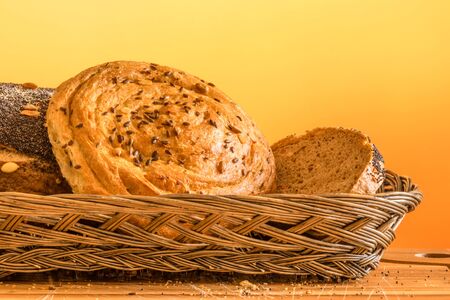 Bread in a basket on a wooden table with orange background