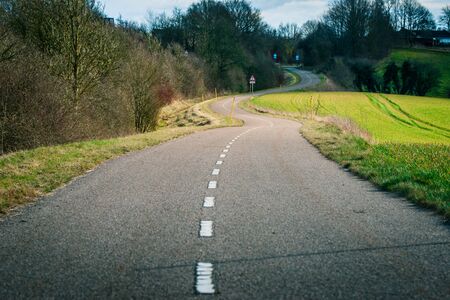Curvy asphalt road in a countryside sceneryの写真素材