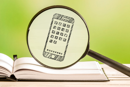 Smartphone search with a pencil drawing of a phone in a magnifying glassの写真素材
