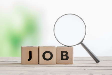 Job word with a magnifying glass on a wooden deskの写真素材