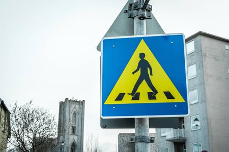 Pedestrian crossing sign in blue and yellow in a big cityの写真素材