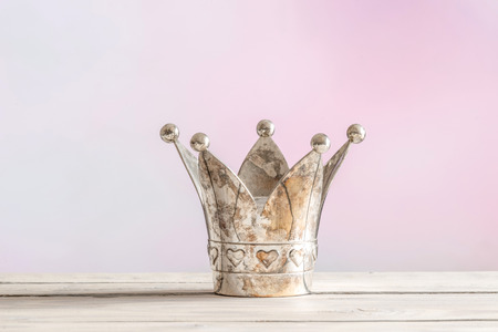 Royal crown on a wooden table on a pink backgroundの写真素材