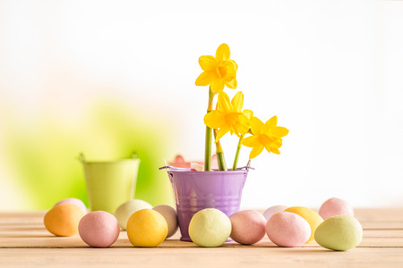Easter eggs on a wooden table with yellow daffodils