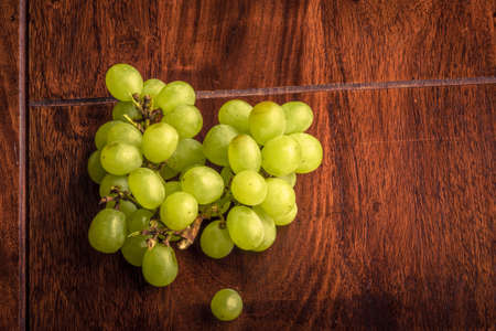 Pile of green grapes on a dark wooden tableの写真素材
