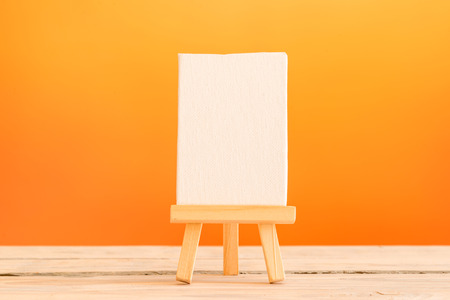 Canvas on a tripod on a table with orange backgroundの写真素材