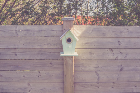 Cute birdhouse on a wooden fence in a gardenの写真素材
