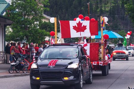 BANFF, CANADA - JULY 1 - 2016: Parade at Canada Day in Banff with canadian flags and crowd looking at passing carsのeditorial素材