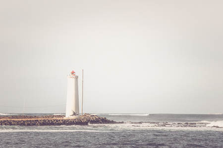 Lighthouse on a small island in the oceanの写真素材