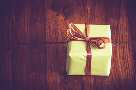 Green gift with a ribbon on a dark wooden tableの写真素材