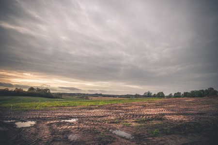 Landscape with wheel tracks on a muddy field in autumn in cloudy weather in off-road terrainの写真素材