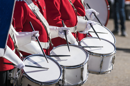 Drummers in red uniforms on a row at a spring parade with white gloves drumming on drumsの写真素材