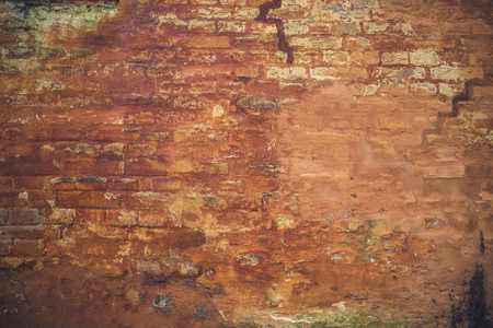 Grunge brick wall with peeling orange paint on an old houseの写真素材