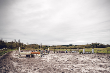 Horse riding track with jump hurdles in an arena with sand in dark cloudy weatherの写真素材