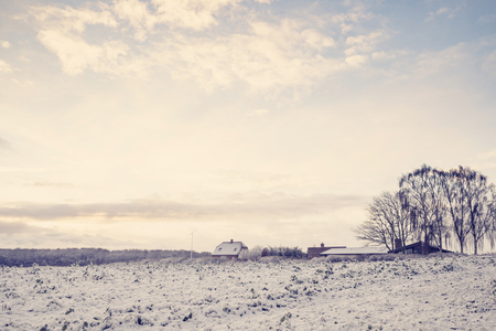 Winter landscape with a small farm house on a rural field with snow in the sunriseの写真素材