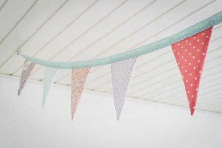 Colorful birthday flags in pastel colors hanging from a ceiling in bright playroomの写真素材