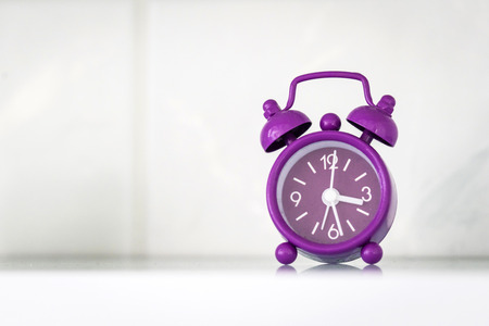 Purple alarm clock in a bright room showing the time
