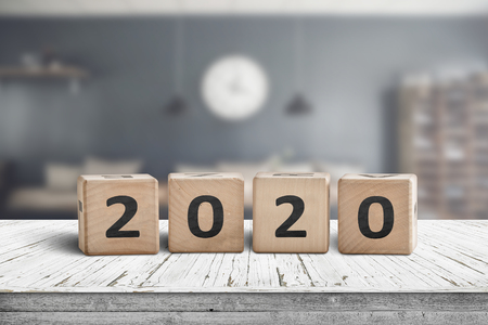 Year 2020 sign on a wooden desk in a cozy kitchen with a blurry background