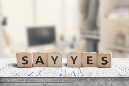 Say yes sign on a wooden desk in a bright room with a blurry backgroundの写真素材