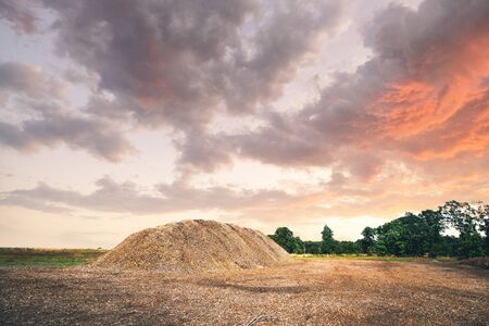 Mulch pile in the summer sunset in a rural landscape with dramatic skyの写真素材